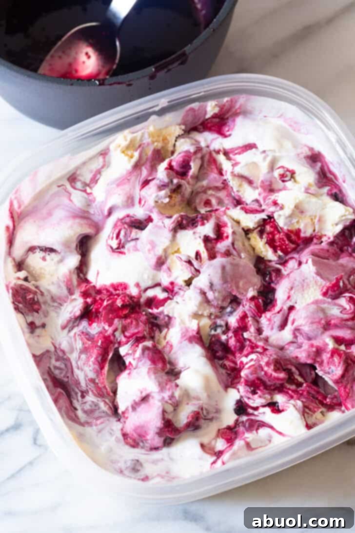 Plastic tub filled with finished blueberry pie ice cream, ready to be frozen and served.