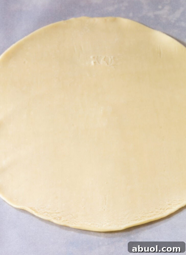 Rolled out circle of pie dough on parchment paper, ready for baking.