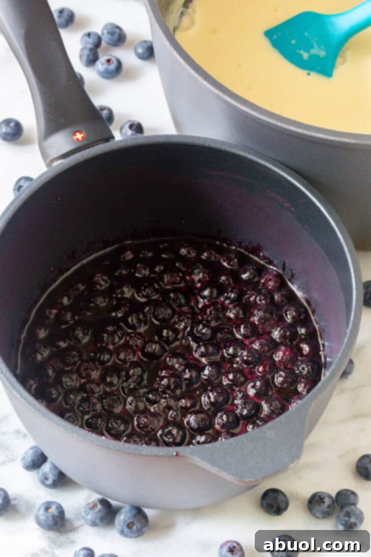 Cooking fresh blueberries in a metal pot, creating a vibrant, jam-like filling.