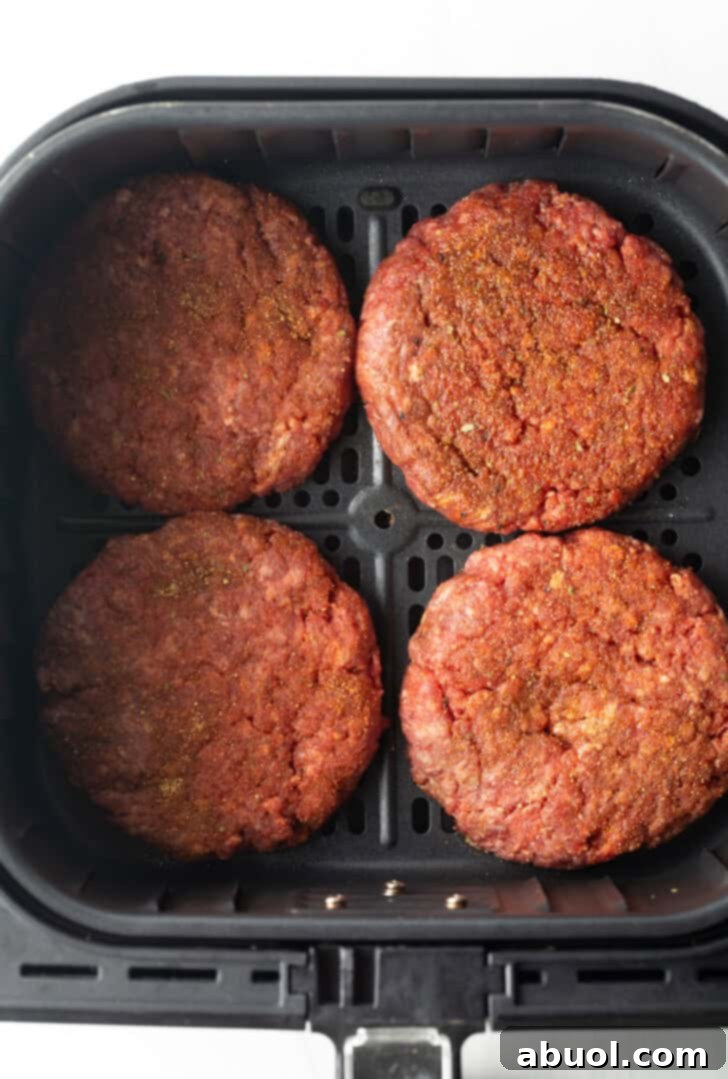 Air Fryer Burger Perfection 6 Top down view 4 hamburger patties in an air fryer basket.