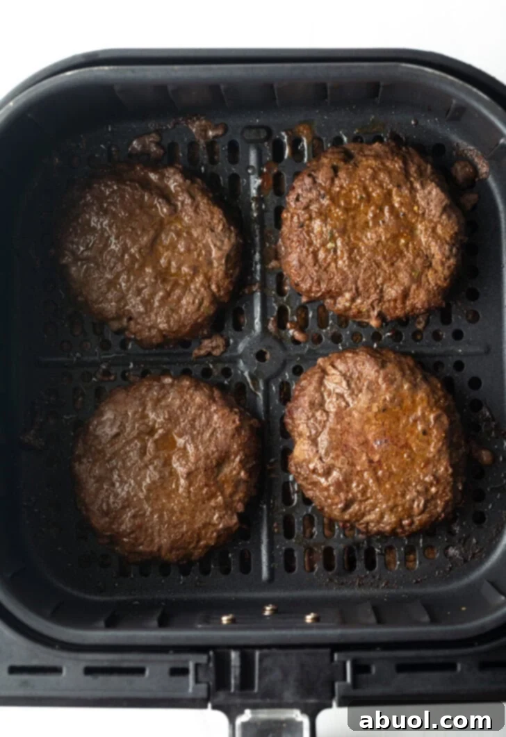 Air Fryer Burger Perfection 7 Top down view 4 burgers in an air fryer basket.