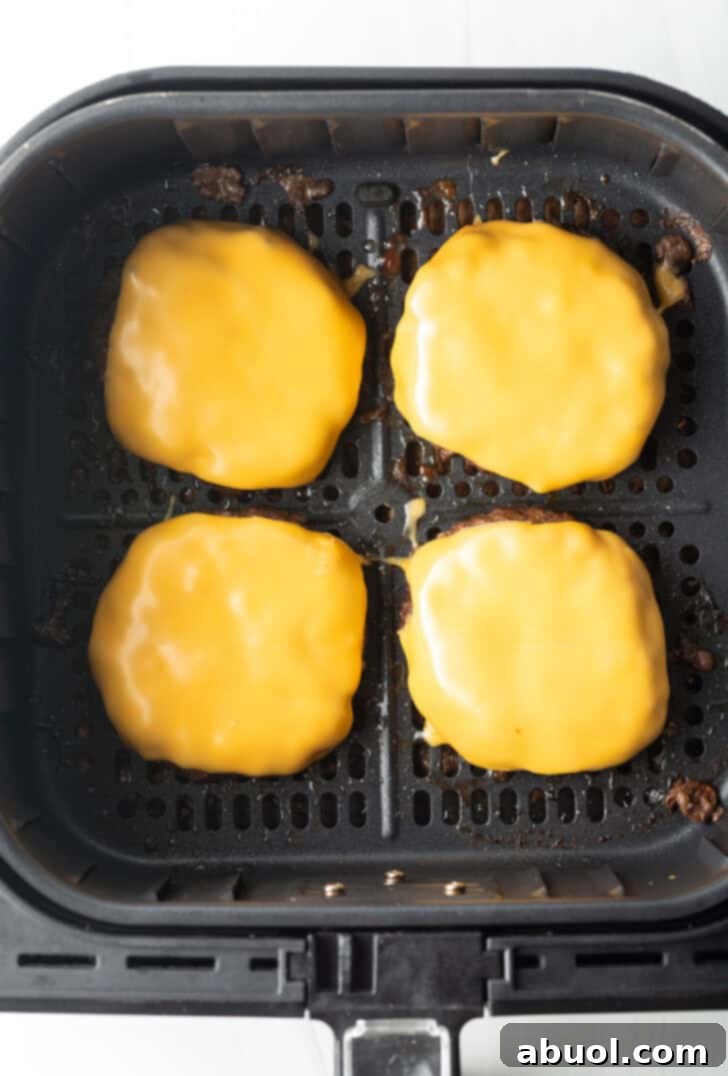 Air Fryer Burger Perfection 8 Top down view 4 cheeseburgers in an air fryer basket.
