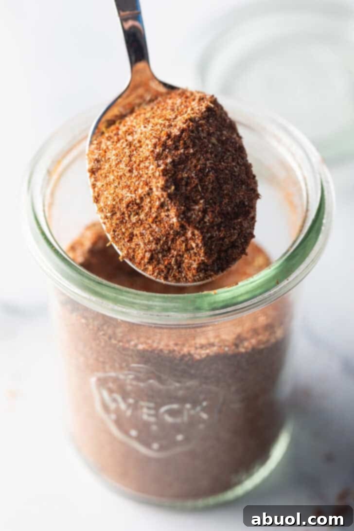 A spoonful of vibrant homemade chicken taco seasoning held towards the camera, showcasing its rich colors.
