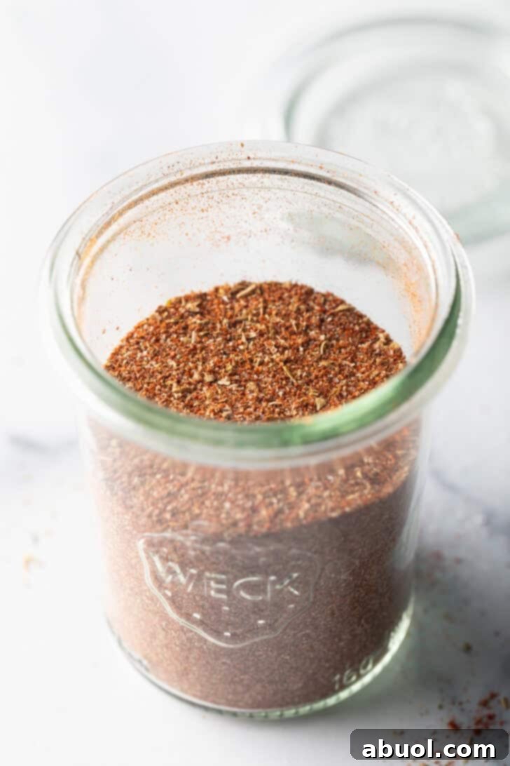 A tall glass jar filled with a perfectly blended homemade taco seasoning, ready for storage or use.
