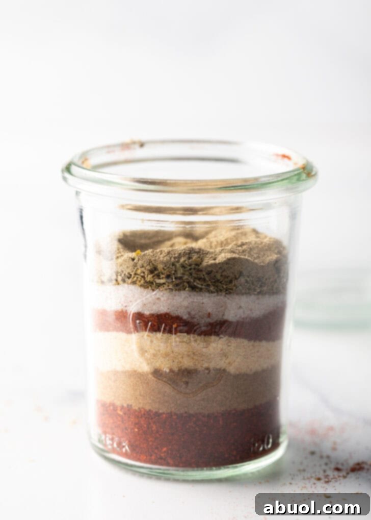 Another view of the layered spices in a tall glass jar, highlighting the blend's components.