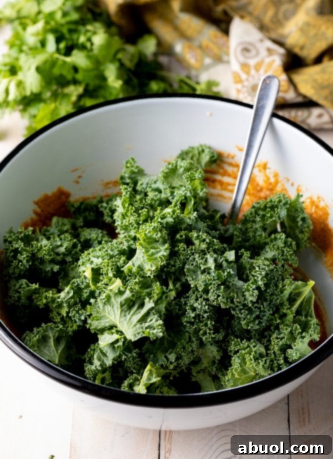 Crispy Kale and Vegetable Pakora 8 Kale with sauce and spices in a white mixing bowl.