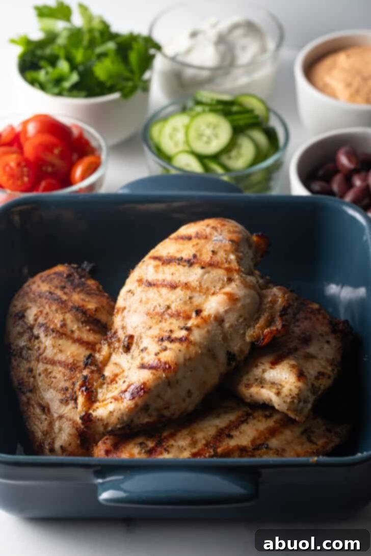Grilled chicken breasts arranged in a blue square baking dish, showcasing their golden-brown char.