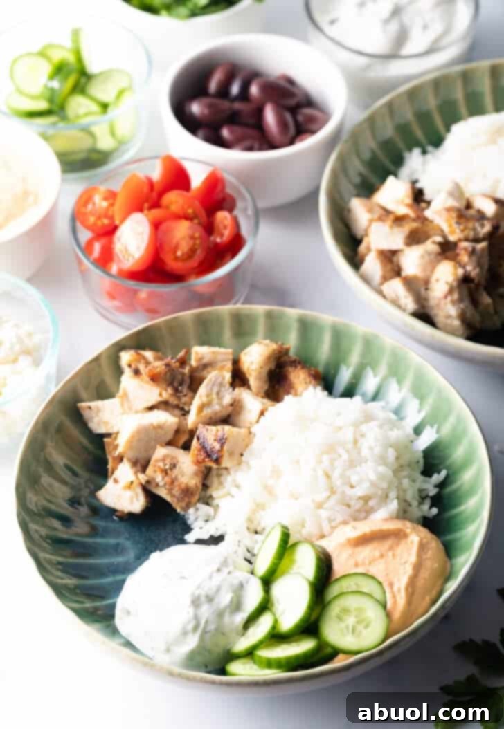 A close-up of a vibrant Greek chicken bowl with a focus on the fresh ingredients like tomatoes, cucumbers, and feta.