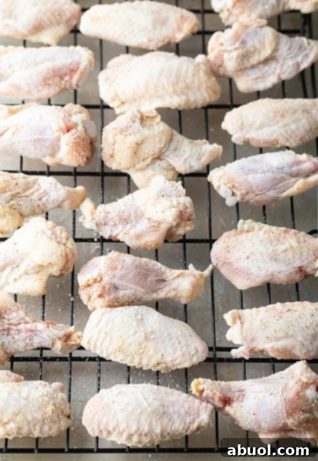 Raw chicken wings and drumettes neatly arranged on a wire rack, elevated above a baking sheet to allow for even air circulation during baking.