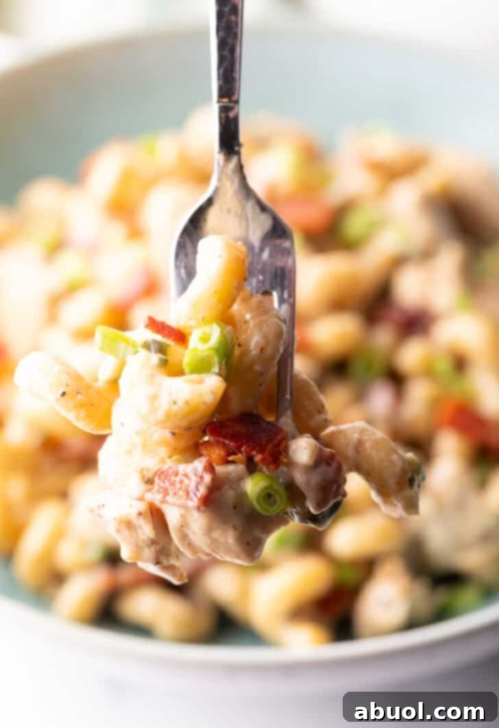 A forkful of savory chicken bacon ranch pasta held up to the camera, showcasing its creamy texture.