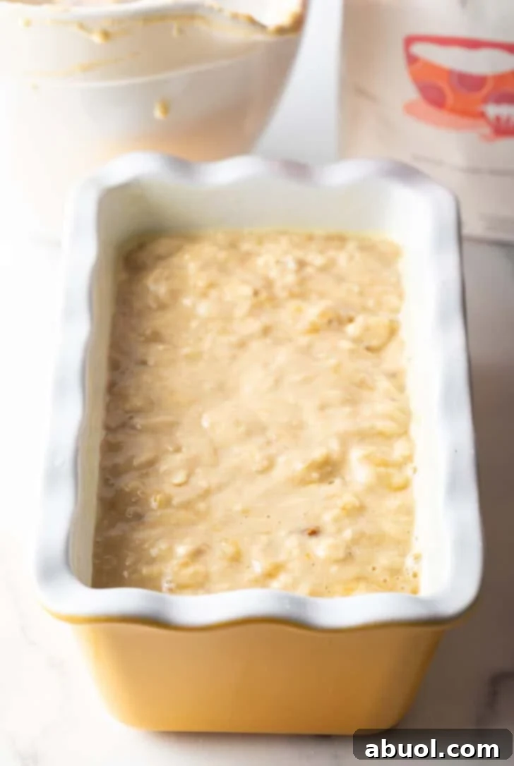 Smooth banana bread batter carefully poured into a pristine white loaf pan, ready for baking.