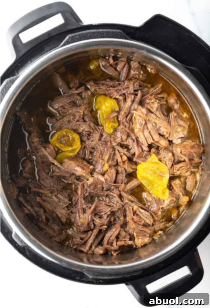 A top-down view inside an Instant Pot, revealing perfectly shredded, tender beef swimming in a rich, savory sauce.