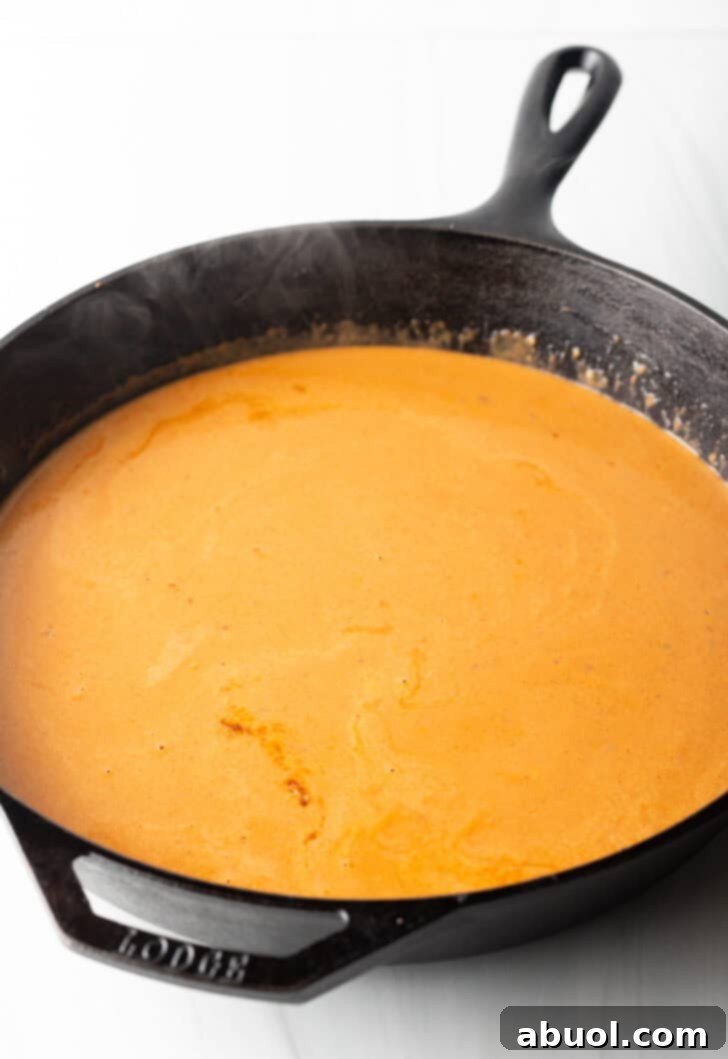 A vibrant, rich tomato cream sauce simmering gently in a cast iron skillet, thick and inviting.