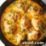 Tuscan Cream Chicken Delights 13 Top-down view of a cast iron skillet packed with chicken thighs in a creamy Tuscan cream sauce.