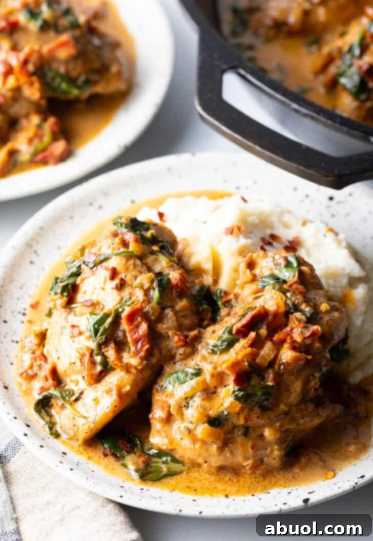 Tuscan Cream Chicken Delights 4 Two pieces of Creamy Tuscan Chicken on a plate, served alongside fluffy mashed potatoes and a generous drizzle of the creamy Tuscan sauce.