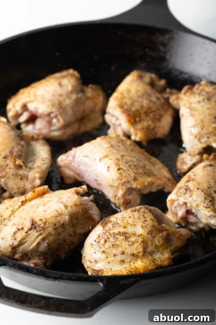 Tuscan Cream Chicken Delights 6 Eight chicken thighs cooking in a large cast iron skillet, browning beautifully.