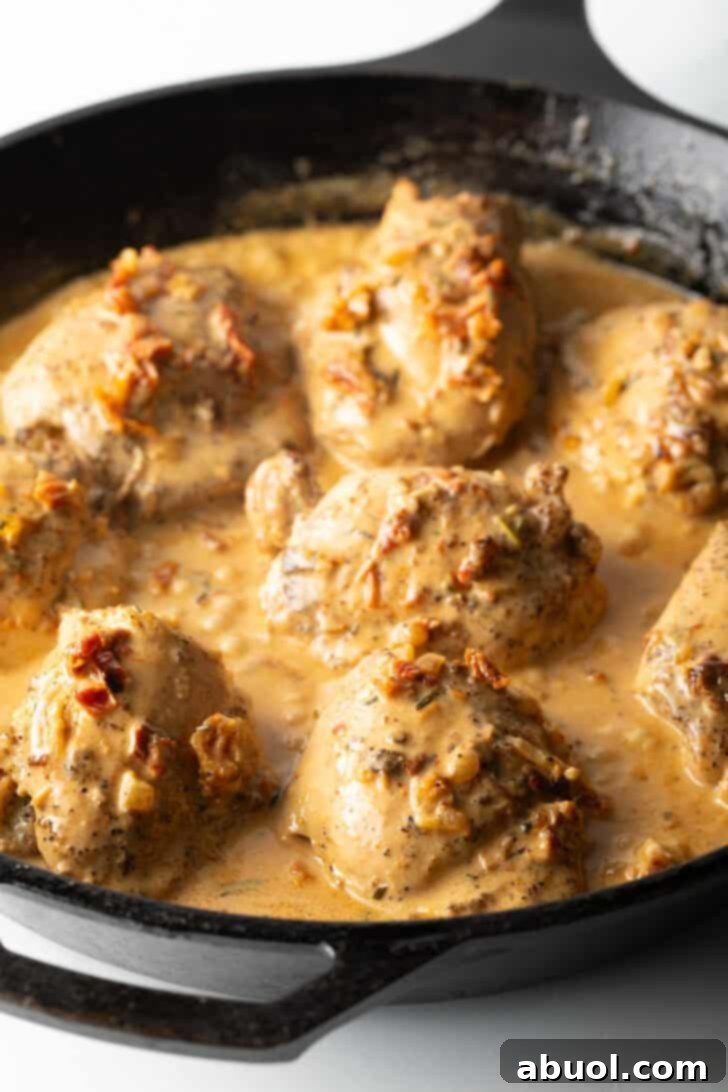Tuscan Cream Chicken Delights 9 Cooked chicken thighs nestled in the creamy sauce within a cast iron skillet.