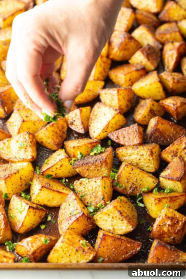 A close-up shot of crispy, golden-brown roasted Yukon potatoes, perfectly cooked and glistening on a baking sheet, ready to be tossed with gremolata.