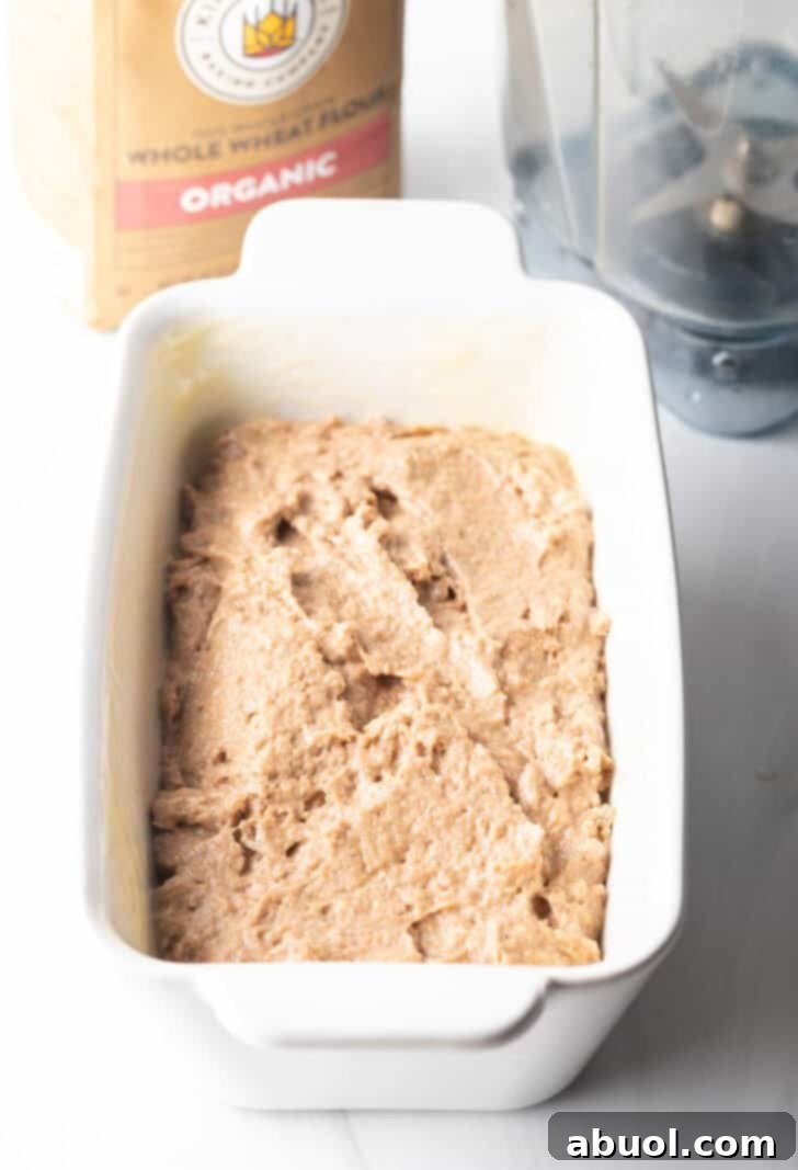 The smooth banana bread batter scooped evenly into a white loaf pan, ready for baking.