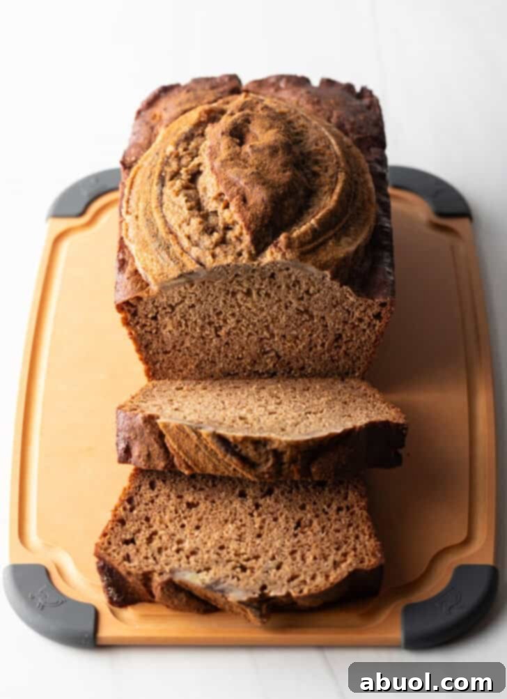 A beautifully arranged loaf of healthy banana bread on a wooden cutting board, with two perfectly layered front slices invitingly presented.