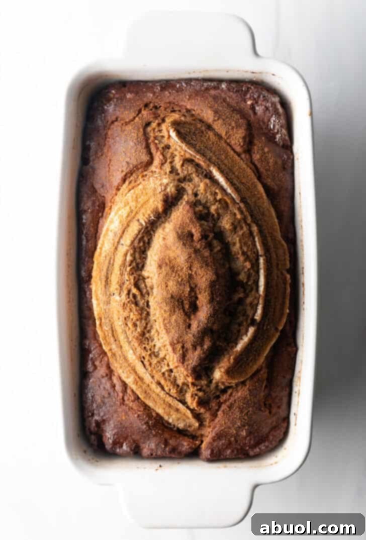 A top-down view of a pristine white loaf pan holding a perfectly baked, healthy banana bread.