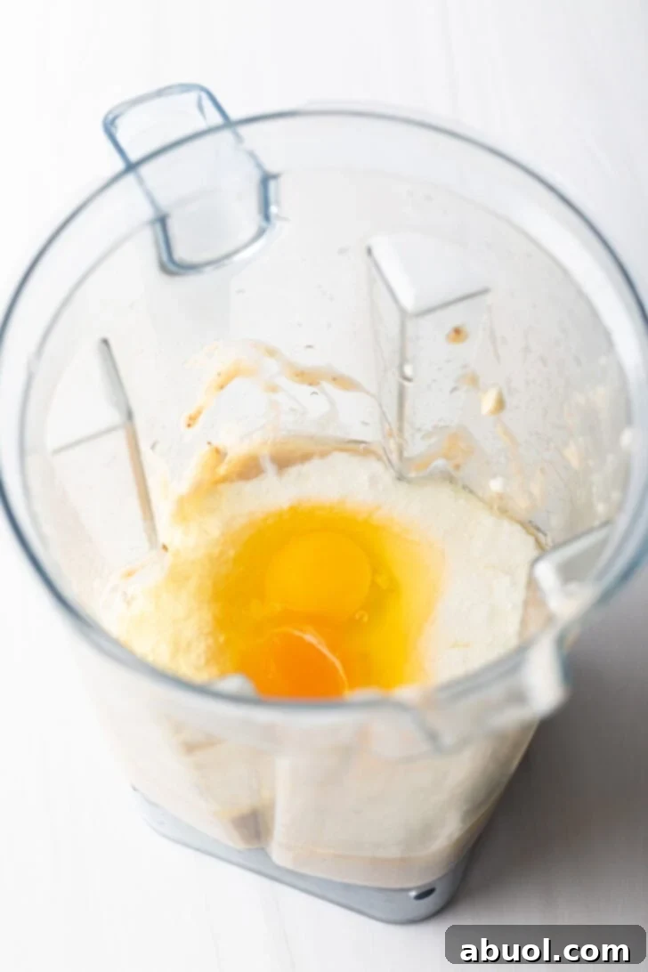 Eggs and cottage cheese being added to a blender jar with bananas.