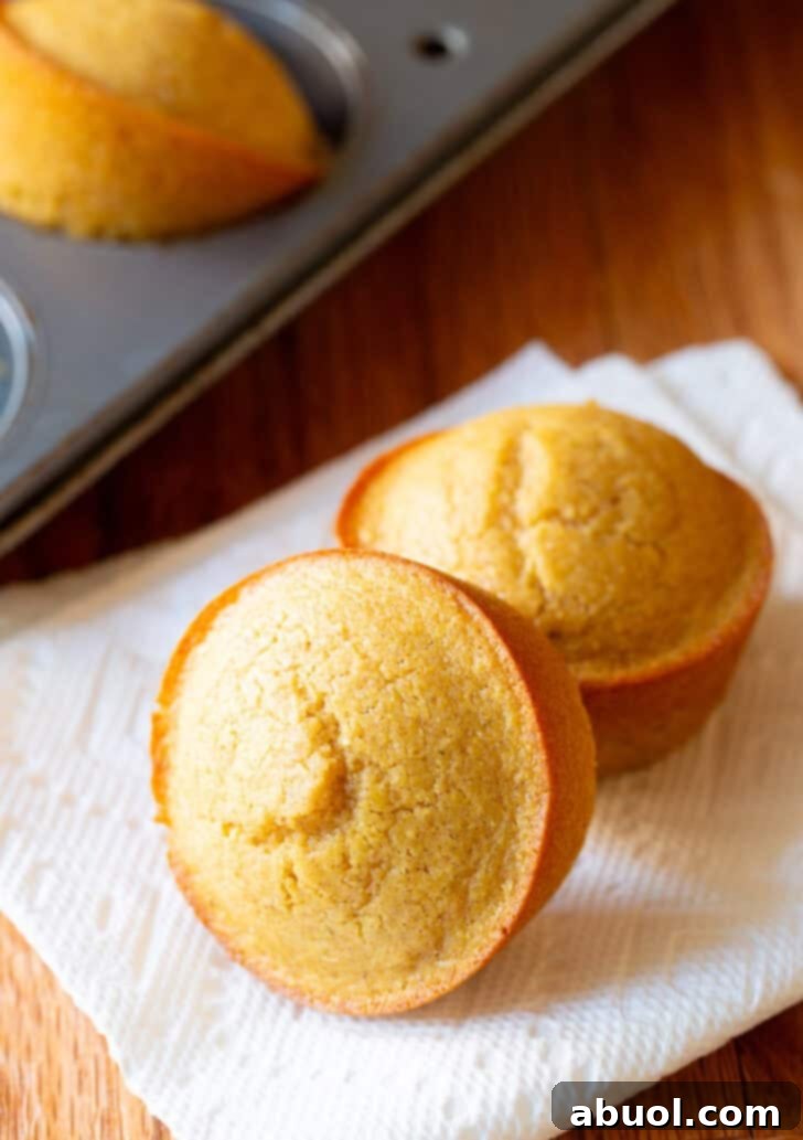 Two honey cornbread muffins on a white napkin.