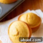 Two honey cornbread muffins on a white napkin.