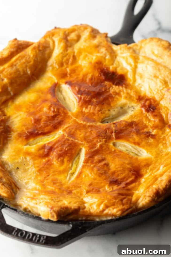 Top down view baked chicken pot pie with golden brown puff pastry crust.