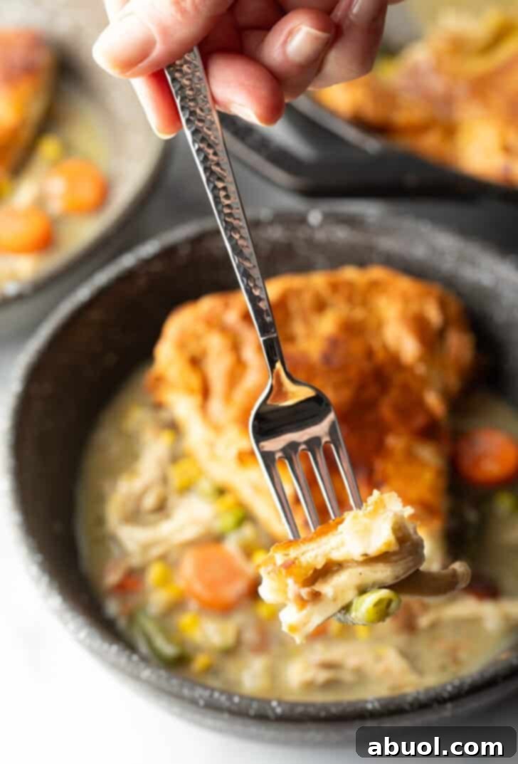 Fork holding a bite of chicken pot pie to camera.