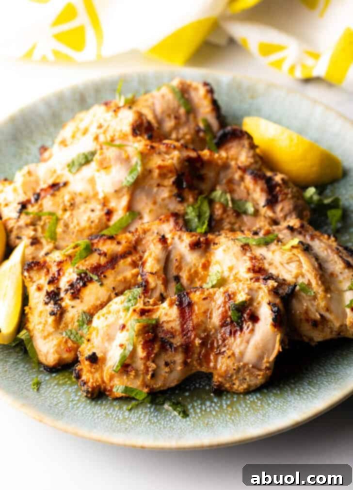 Grilled marinated chicken thighs in a shallow blue bowl, ready to be served.