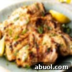 Grilled marinated chicken thighs in a shallow blue bowl, ready to be served.