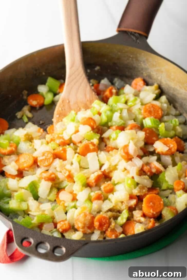 Sauteeing chopped carrots, celery, and onion in a cast iron skillet.