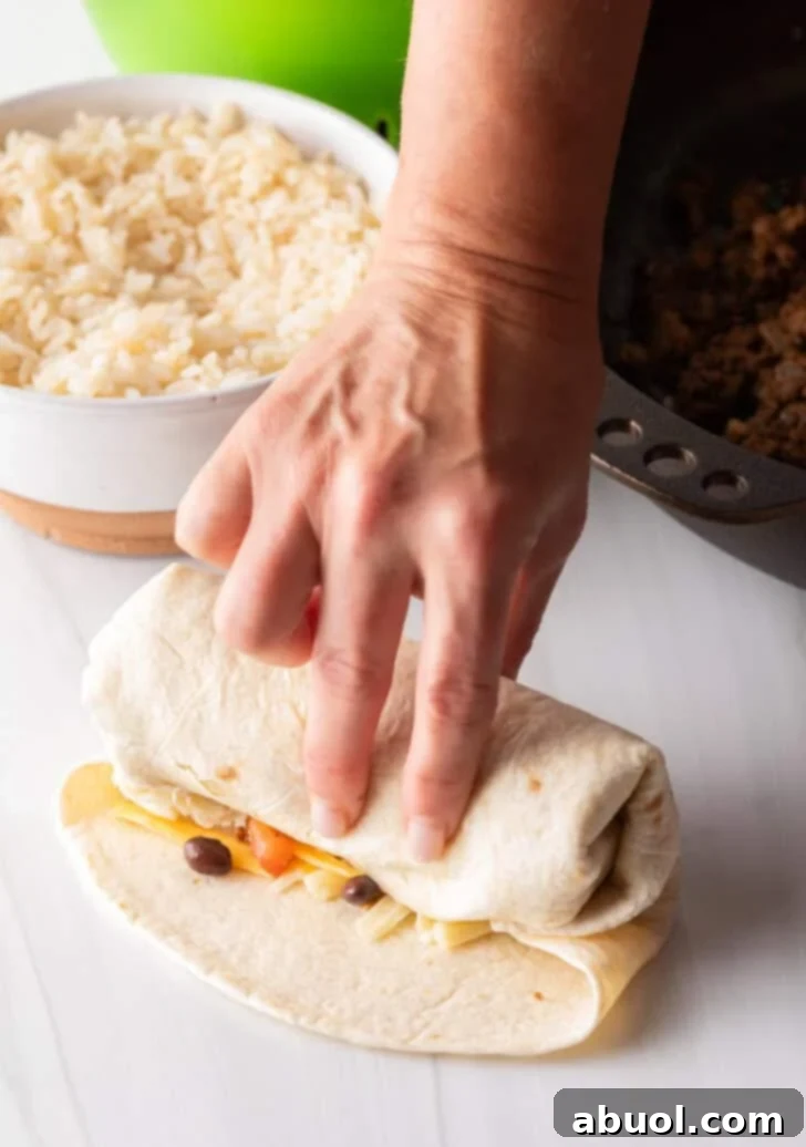 Hand wrapping a beef burrito.