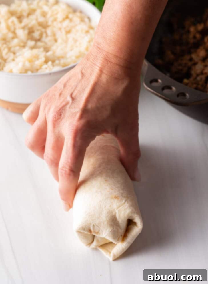 Hand wrapping a beef burrito.