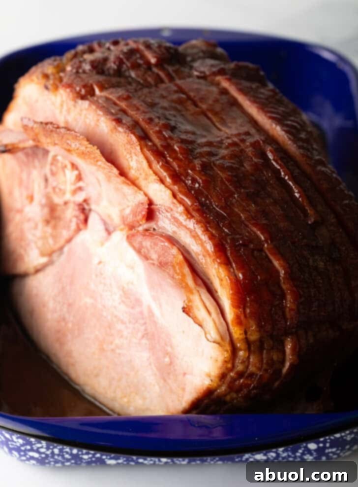 A perfectly cooked spiral ham, glistening with glaze, resting in a blue and white speckled roasting pan, ready to be carved.