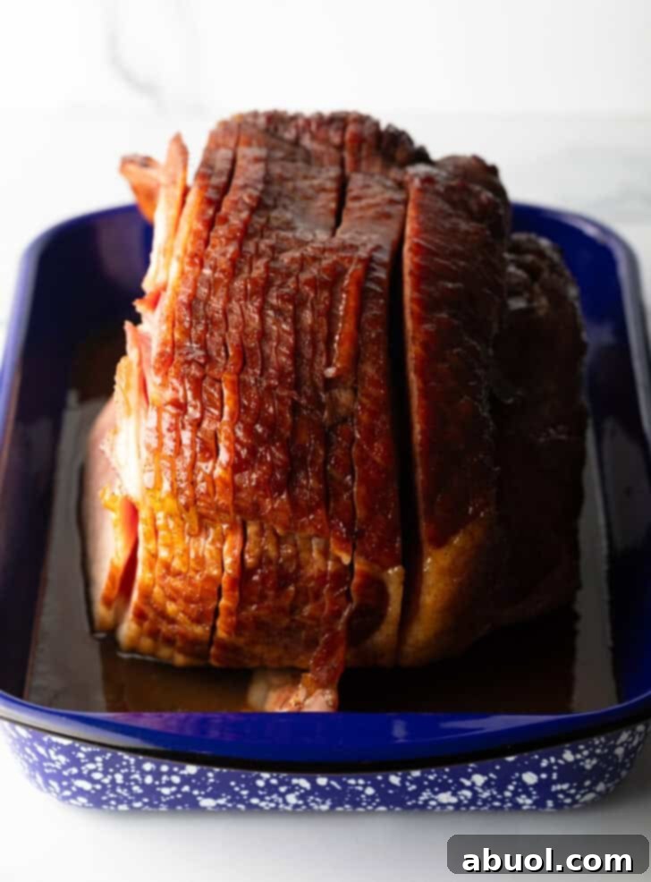 A perfectly cooked and glazed spiral ham in a blue and white speckled roasting pan, ready to be served at a holiday feast.