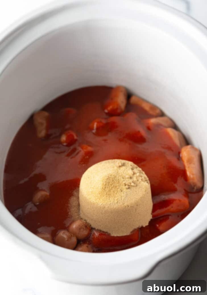 A scoop of brown sugar added to the slow cooker with smokies and barbecue sauce.