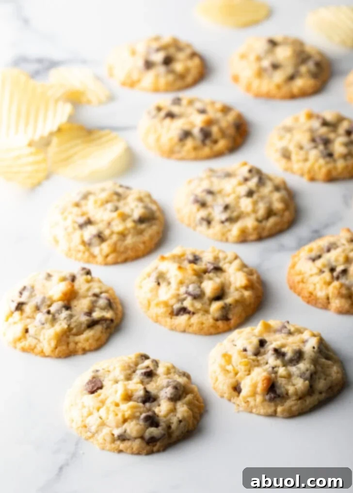 Salty Sweet Crunch Cookies 2 Overhead view of perfectly baked chocolate chip potato chip cookies on a marble surface next to a bowl of potato chips.