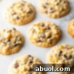 Salty Sweet Crunch Cookies 13 Baked potato chip cookies on a white surface, showcasing their golden edges and melty chocolate.