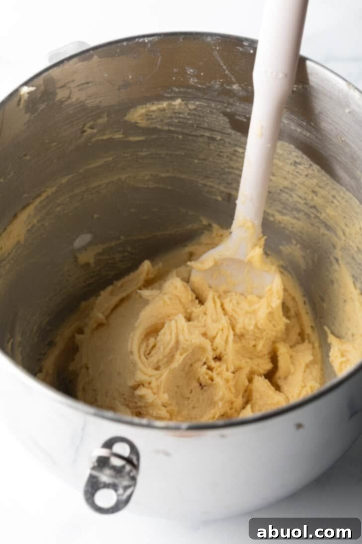 Salty Sweet Crunch Cookies 7 Potato chip cookie batter in a metal bowl, being stirred with a white spoon.