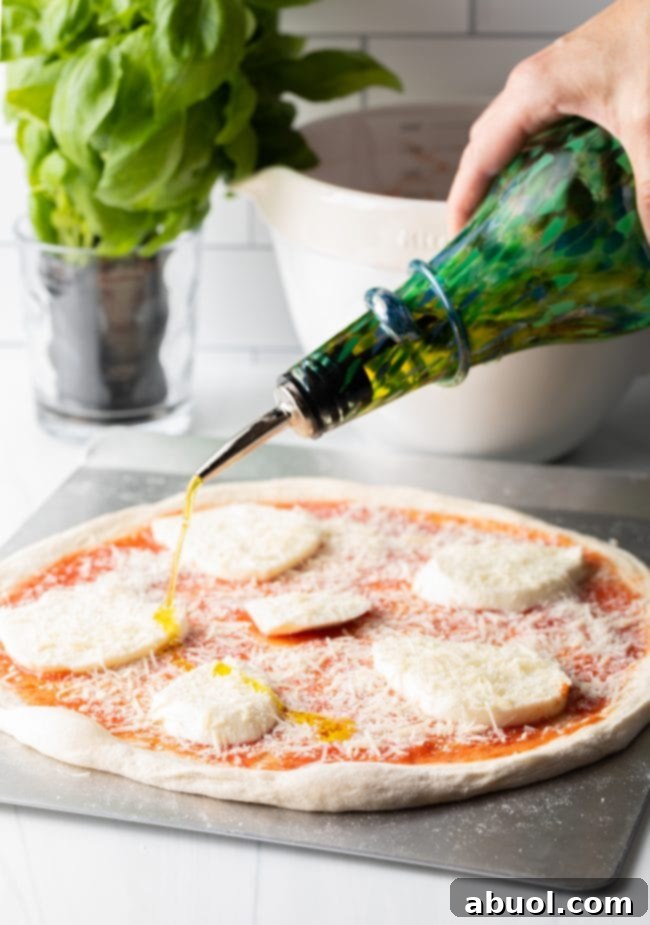 Crafting Perfect Neapolitan Pizza Dough 15 Drizzling olive oil over slices of mozzarella cheese on an unbaked pizza.