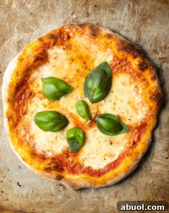 Crafting Perfect Neapolitan Pizza Dough 4 Top down view of a baked Neapolitan pizza with fresh basil leaves.