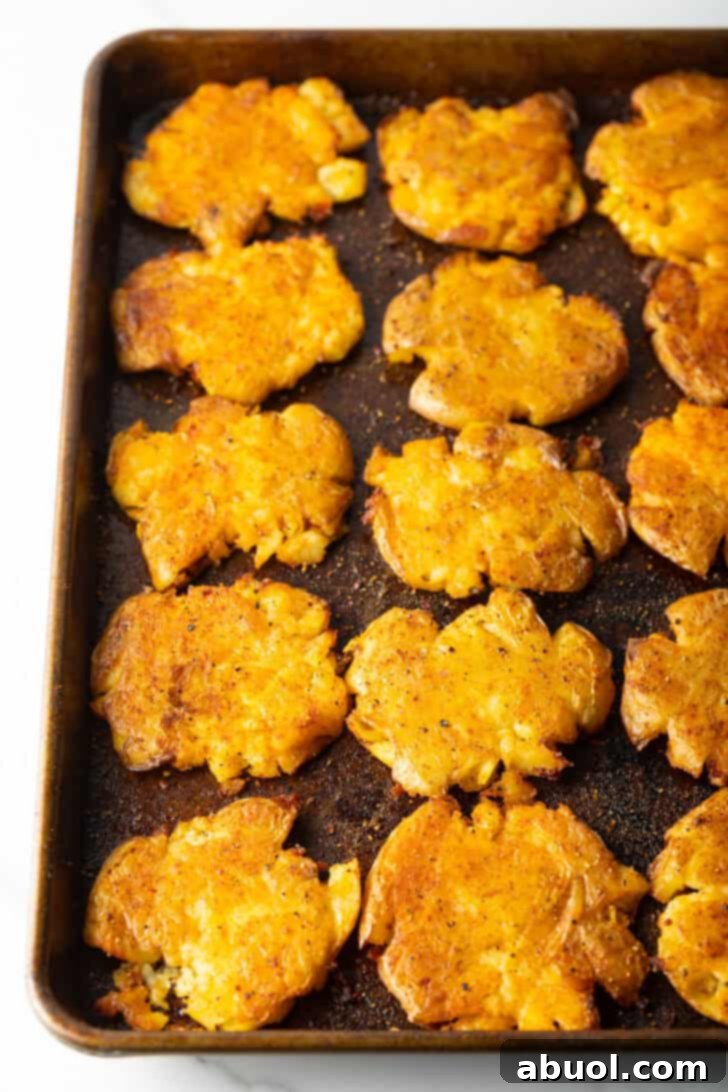 A baking sheet filled with 15 perfectly golden and crispy smashed potatoes, fresh out of the oven and looking incredibly appetizing.