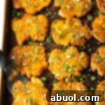 Top down view of 15 golden smashed potatoes on a baking sheet, representing the finished dish.