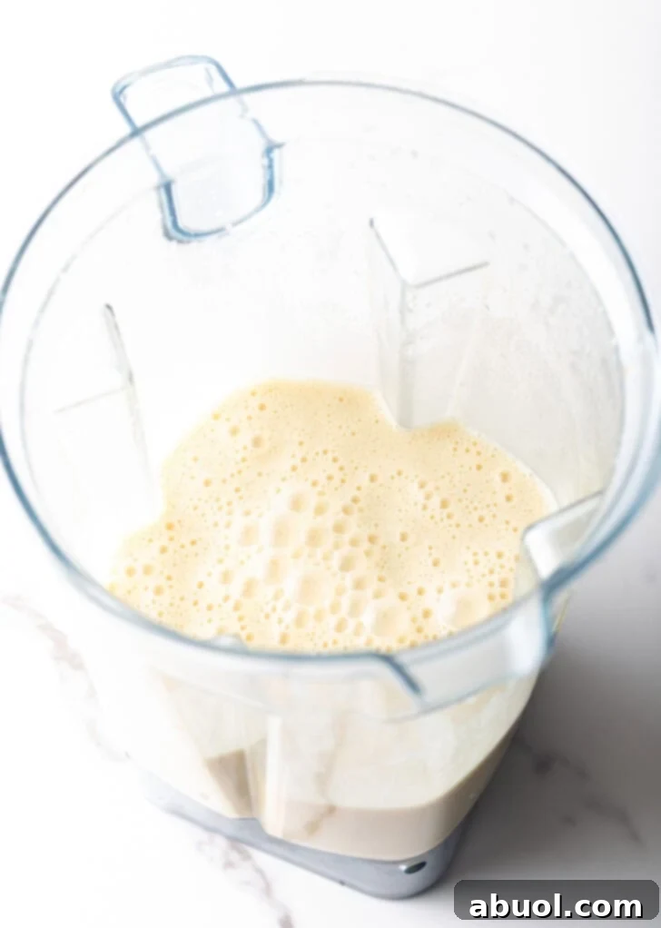 A blender jug filled with smooth, pale yellow Dutch Baby batter, ready to be poured into hot skillets.