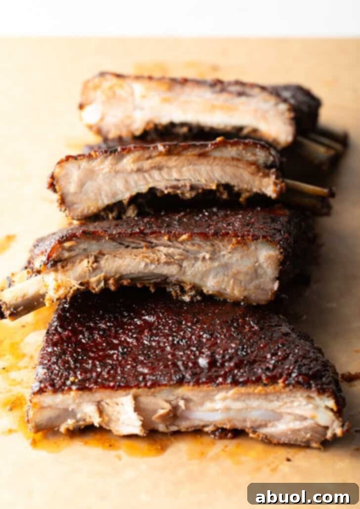 Ultimate St Louis Pork Ribs 2 St. Louis style ribs sliced and stacked on top of each other on a cutting board.