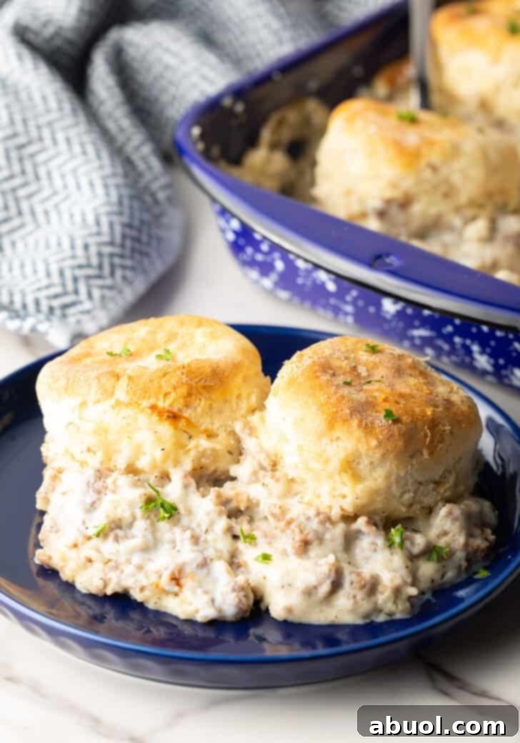 Two biscuits and gravy on a blue plate, a perfect individual serving.
