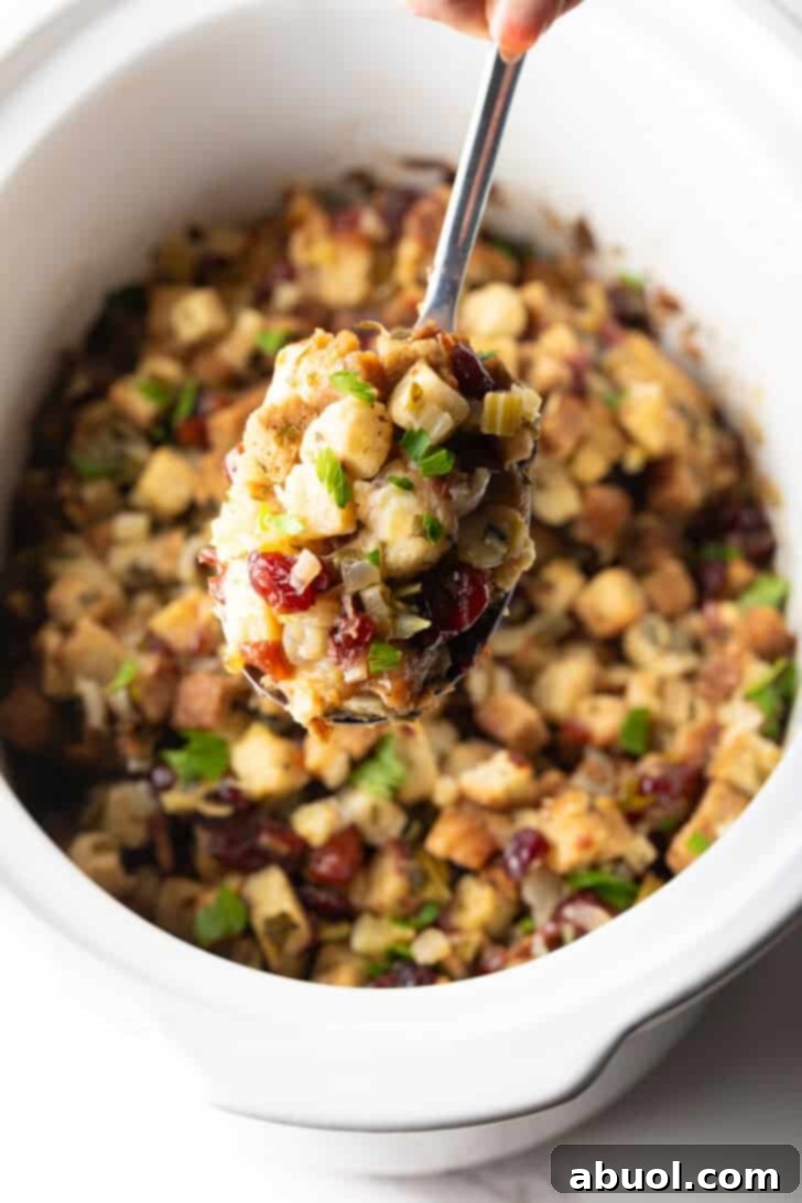 A scoop of crock pot stuffing being held with a metal spoon.