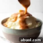 Easy mashed potatoes and gravy with homemade brown gravy being spooned over the mashed potatoes.